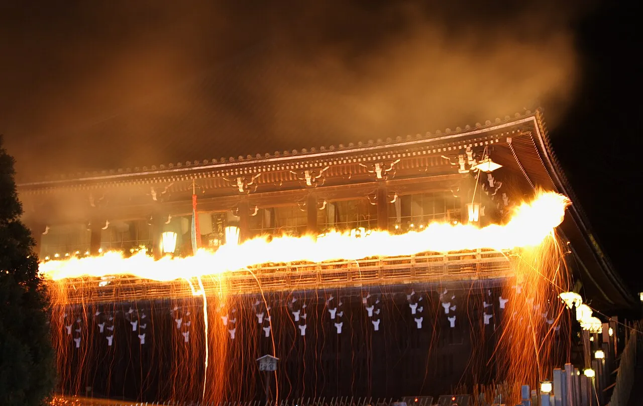 A torch blazes along the balcony of Nigatsu-dō Hall at night, showering sparks down the wooden walls.